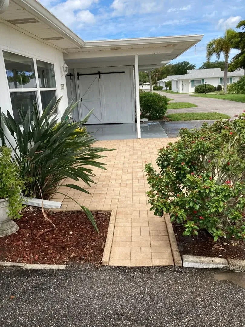 A brick paver walkway between planting beds, cleaned to the even sand colour sealing is meant to hold