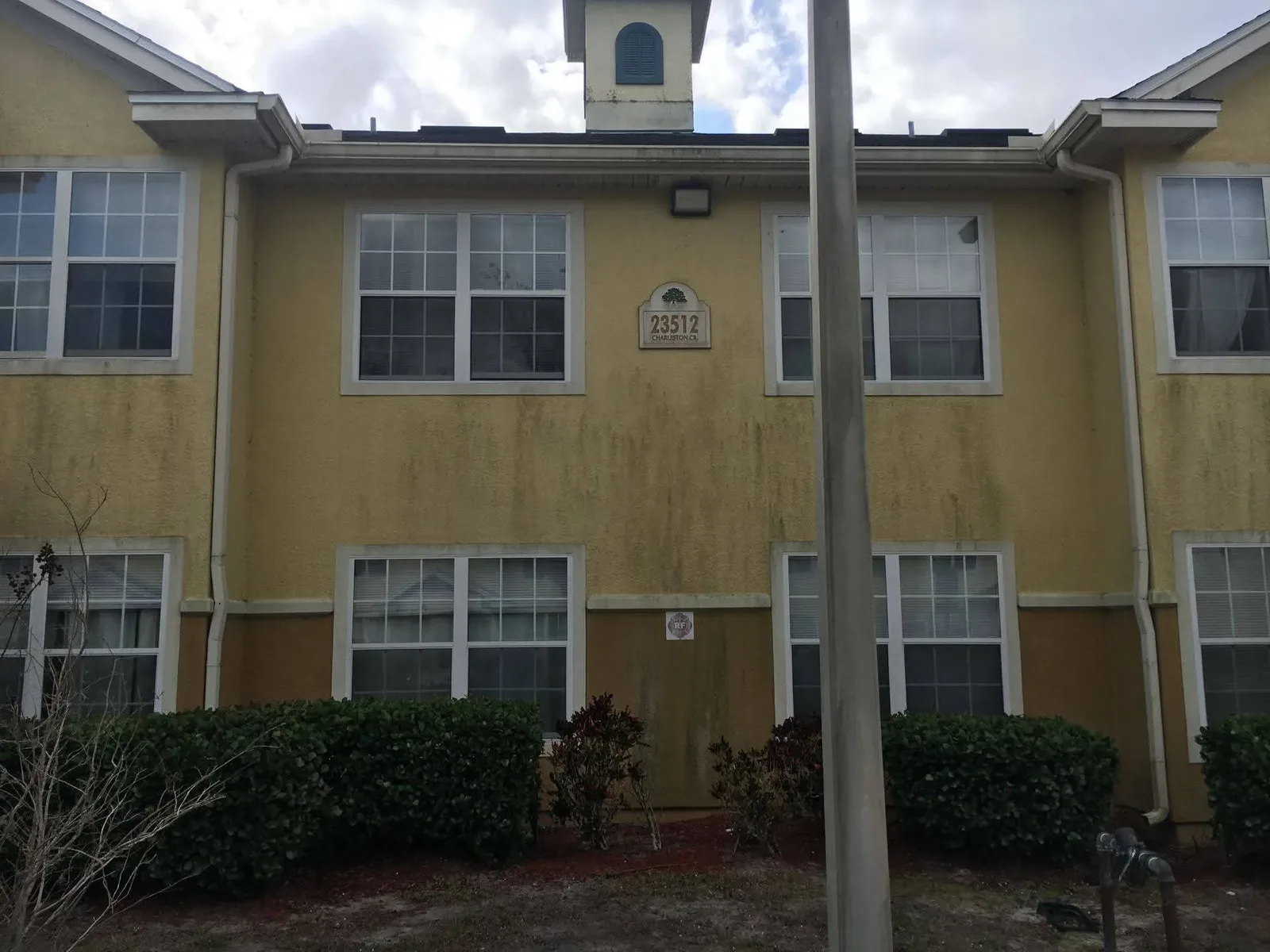 Stucco block wall stained with green algae and grey weathering