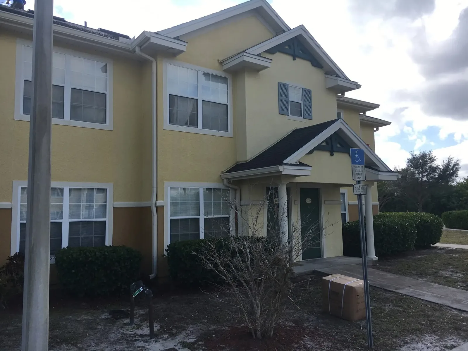 A two storey yellow stucco building after a soft wash, walls and white trim back to an even colour